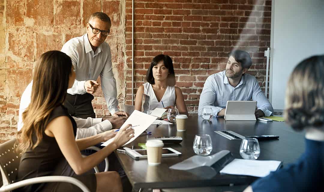 A man calmly points at a woman during a meeting